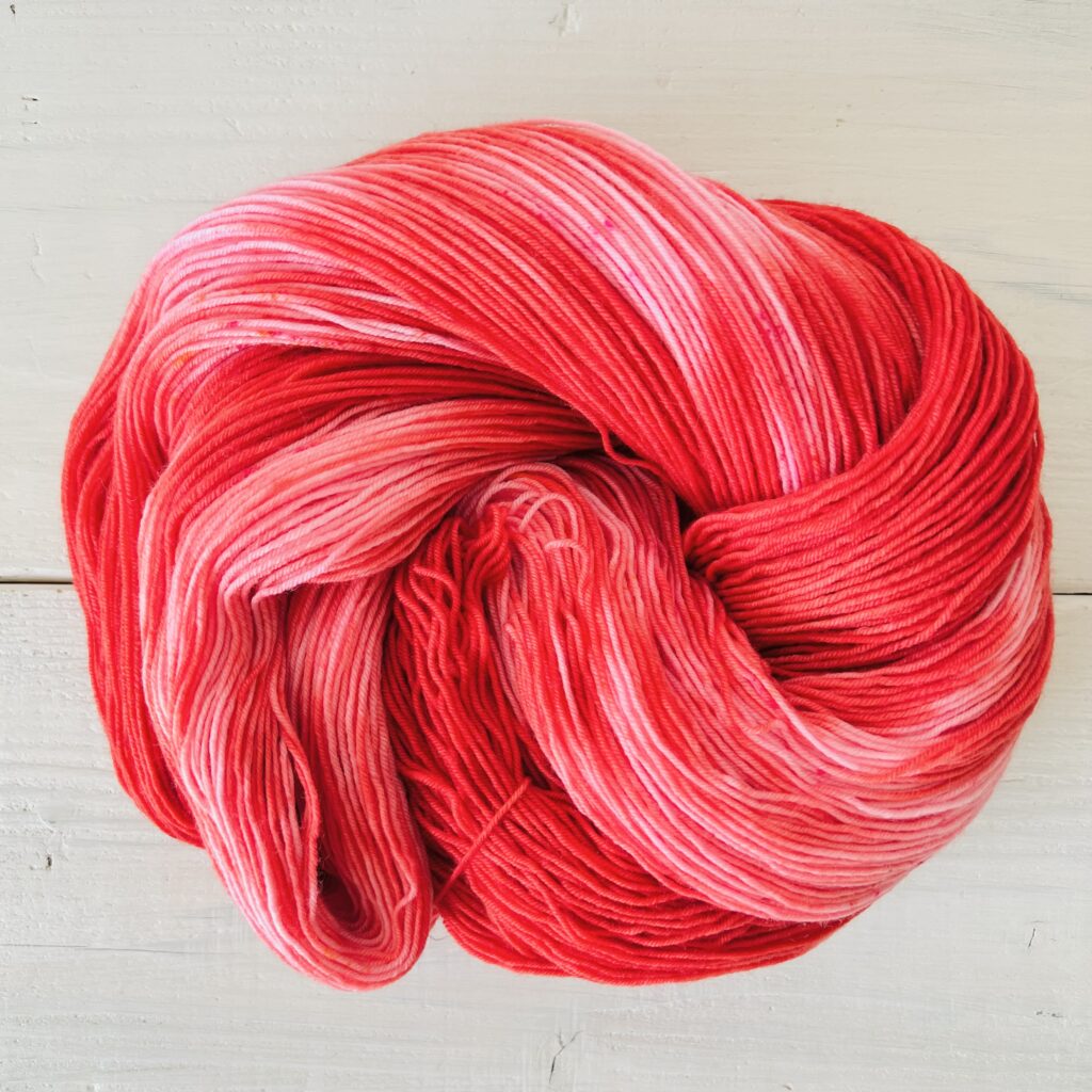 赤とピンクの手染め毛糸のカセをほどいた色の入り方