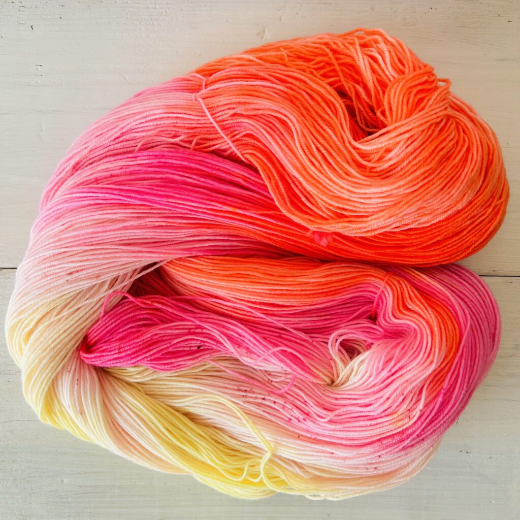 ピンクやイエローやオレンジグラデーションの手染め毛糸のカセをほどいた色の入り方
