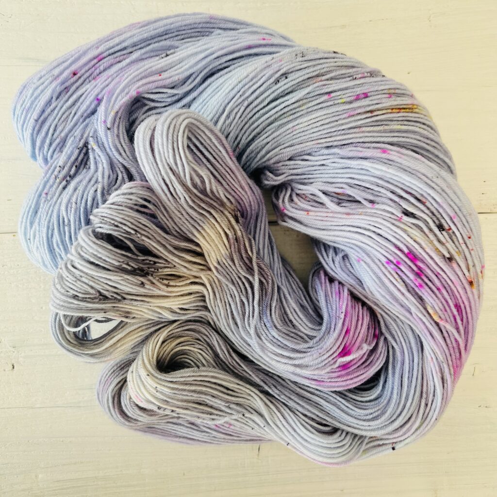ピンクやグレーや甘いパープルグラデーションの手染め毛糸のカセをほどいた色の入り方