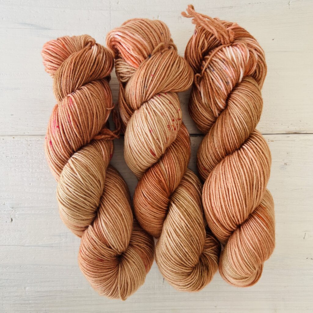 オレンジピンクの光があるようなブラウンの手染め毛糸のカセ全体