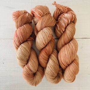 オレンジピンクの光があるようなブラウンの手染め毛糸のカセ全体