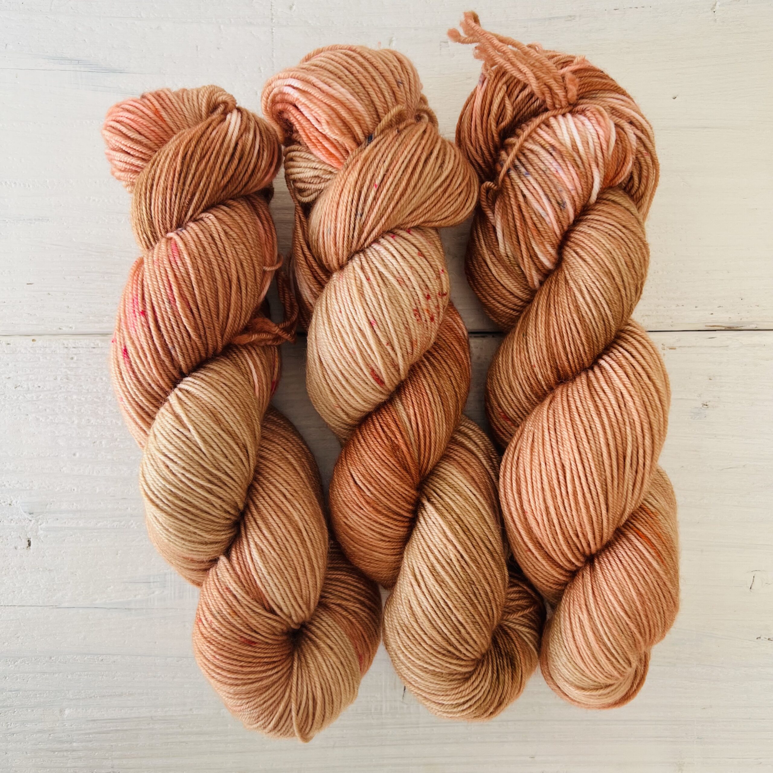 オレンジピンクの光があるようなブラウンの手染め毛糸のカセ全体