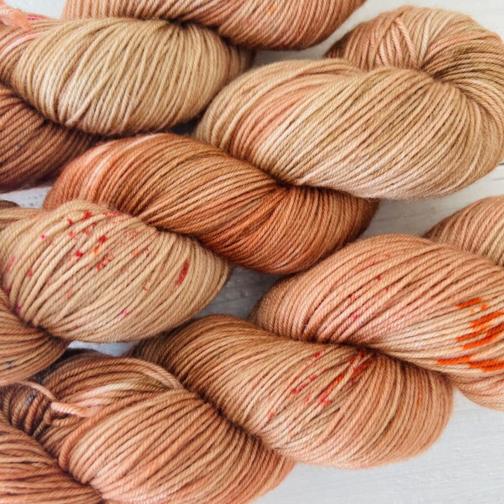 赤み橙色の手染め毛糸のスペックルやグラデーションが見えるアップ