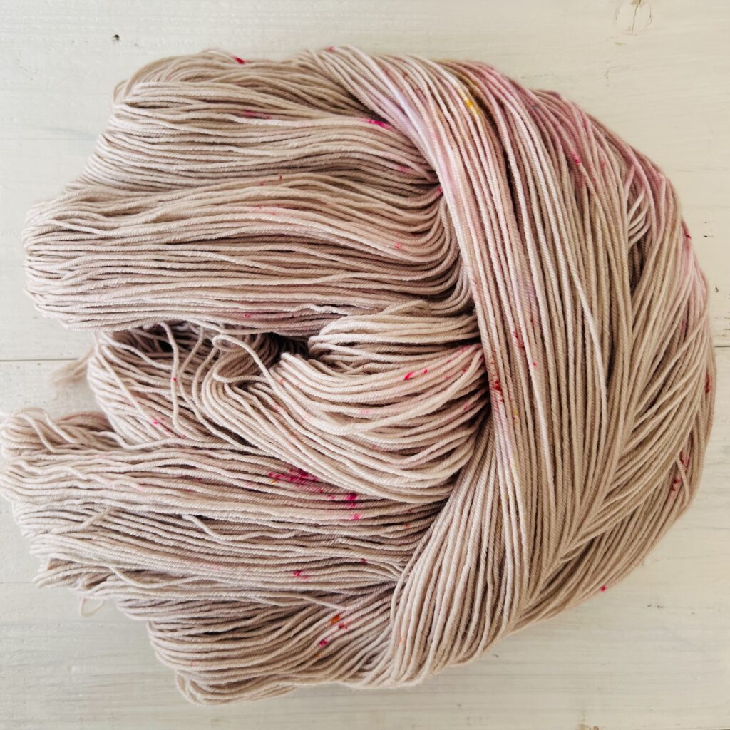 ピンクやグレージュグラデーションの手染め毛糸のカセをほどいた色の入り方