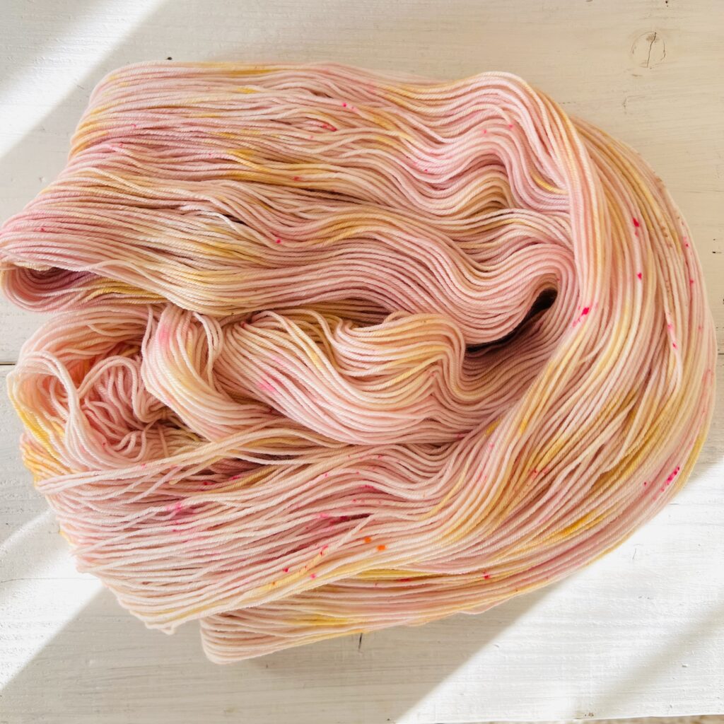 ピンクやイエローグラデーションの手染め毛糸のカセをほどいた色の入り方