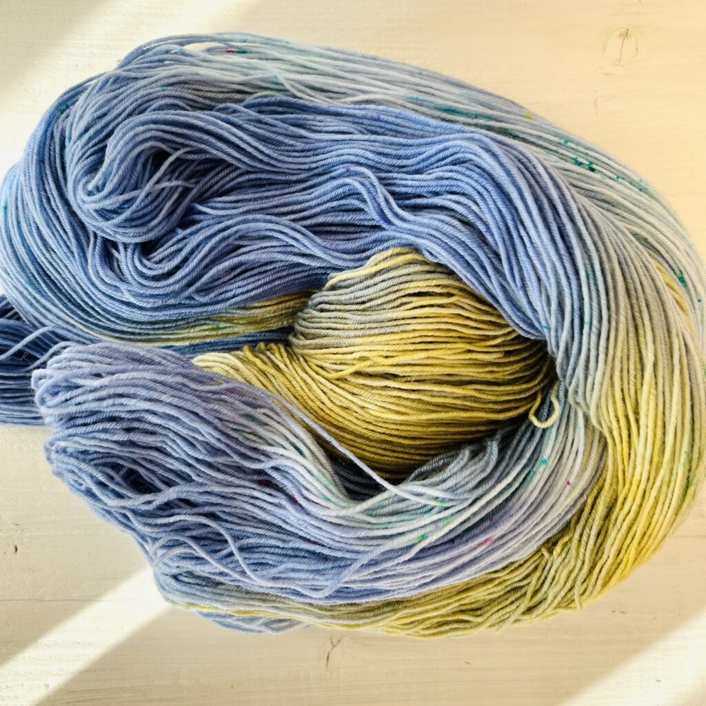 ブルーと渋いイエローのグラデーションの手染め毛糸のカセをほどいた色の入り方