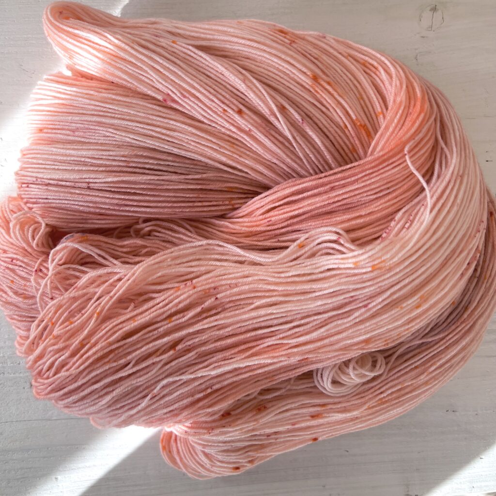 ピンクやオレンジグラデーションの手染め毛糸のカセをほどいた色の入り方