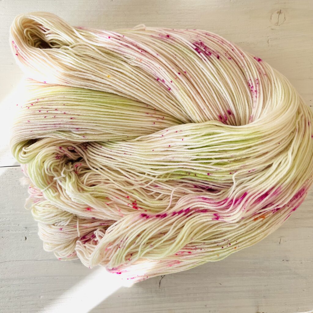 アイボリーやグリーンなどのグラデーションの手染め毛糸のカセをほどいた色の入り方