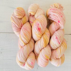 やわらかいピーチピンクとカスタードイエローの手染め毛糸のカセ全体
