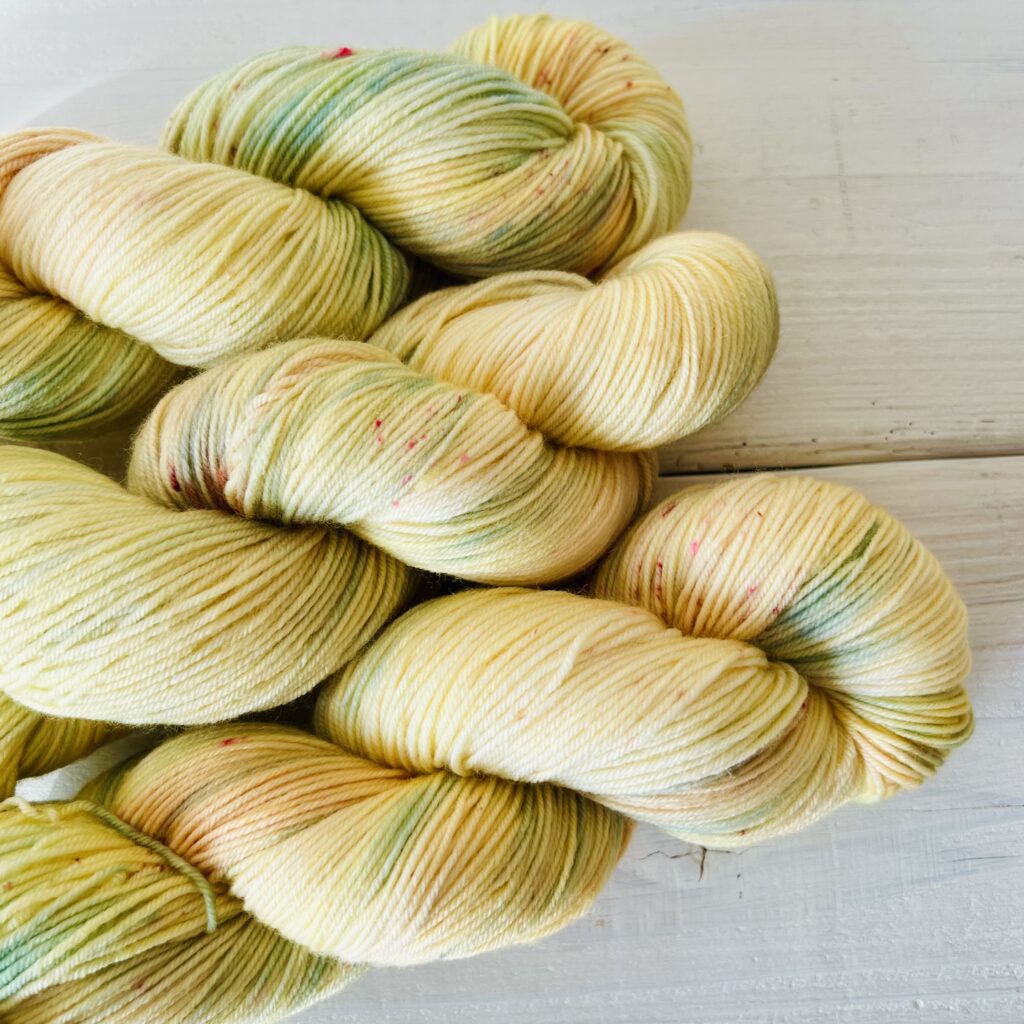 やわらかい光のようなクリームイエロー手染め毛糸のスペックルやグラデーションが見えるアップ