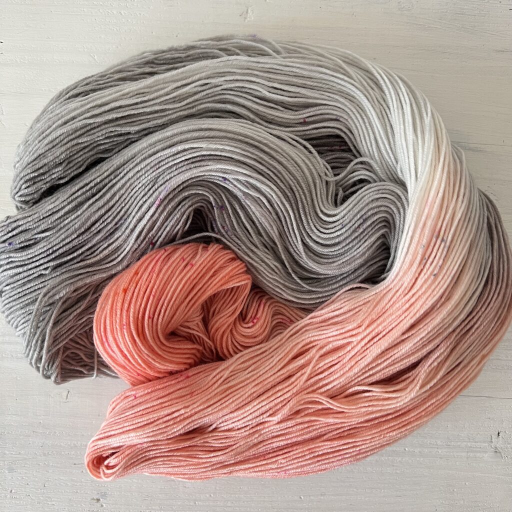 ピンクやグレーのグラデーションの手染め毛糸のカセをほどいた色の入り方