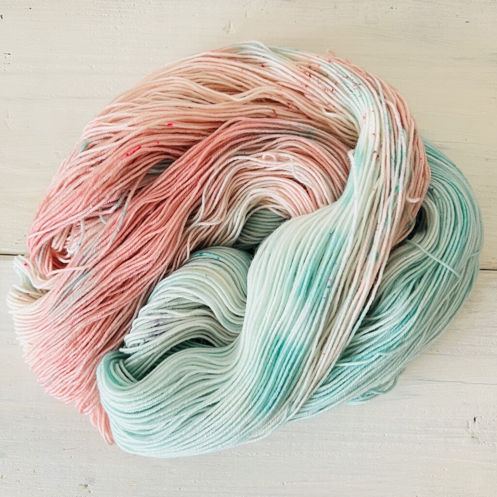 ダスティーピンクからスカイブルーのグラデーションの手染め毛糸のカセをほどいた色の入り方
