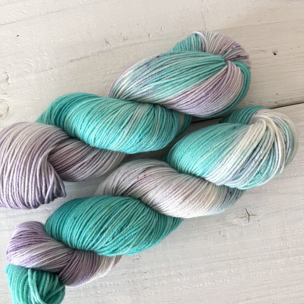 宝石のような青緑色の手染め毛糸のスペックルやグラデーションが見えるアップ