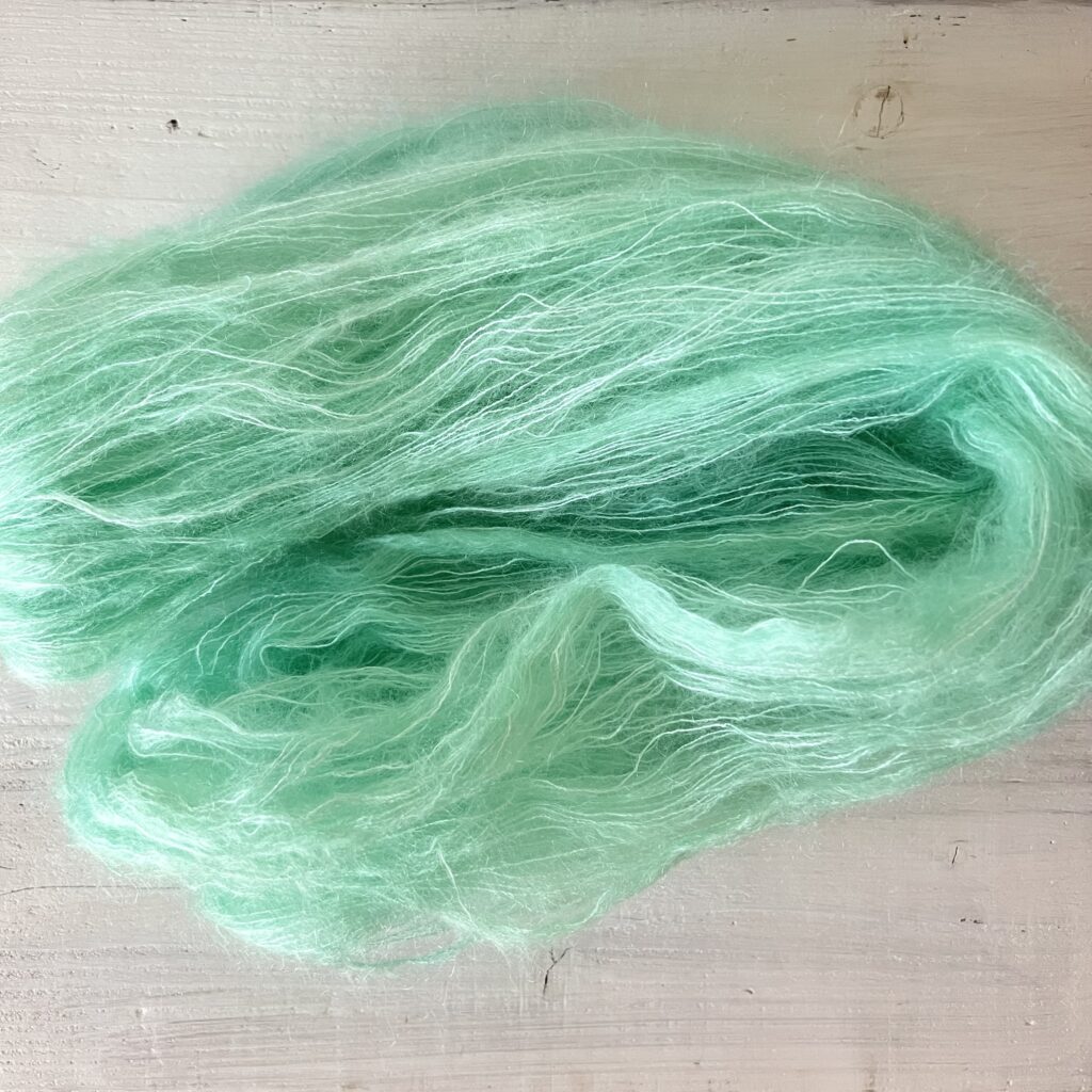 淡いグリーンの手染め毛糸のカセをほどいた色の入り方