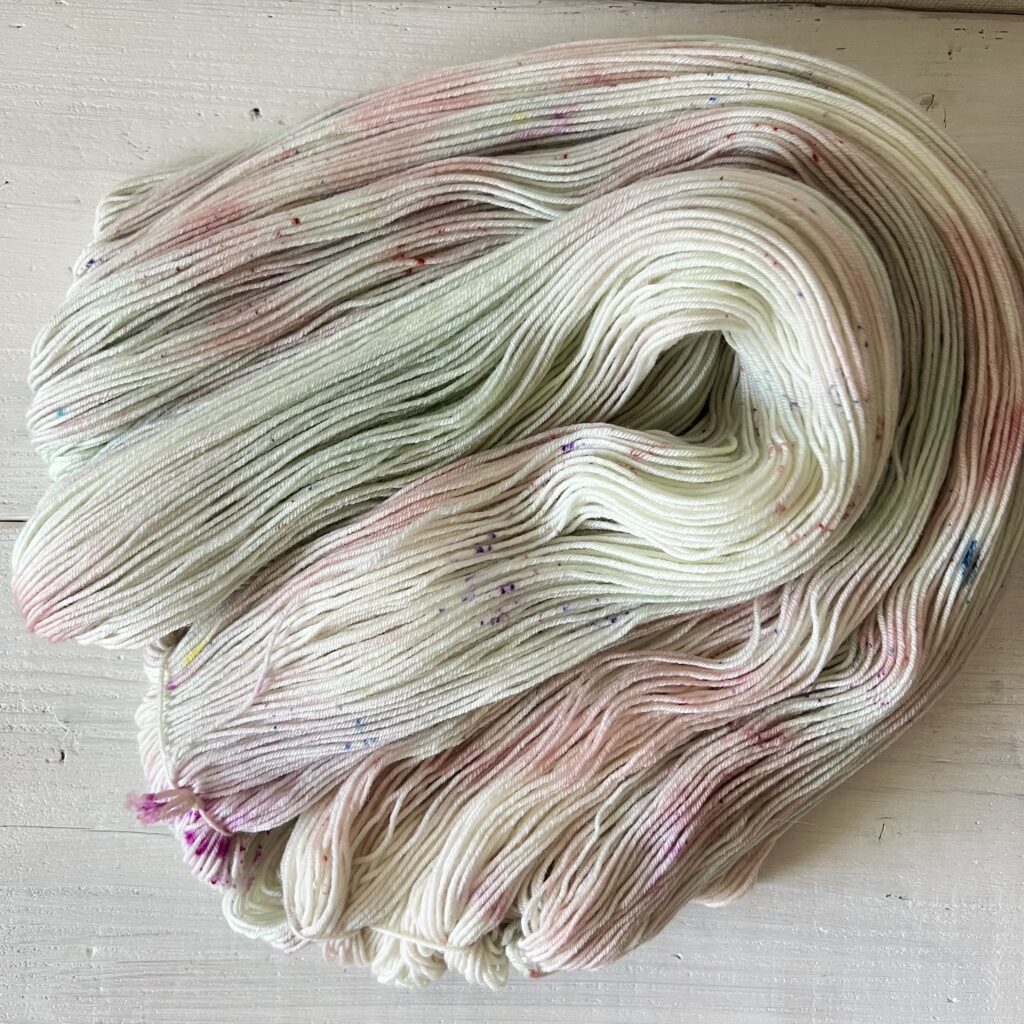 グリーンやくすみピンクの手染め毛糸のカセをほどいた色の入り方