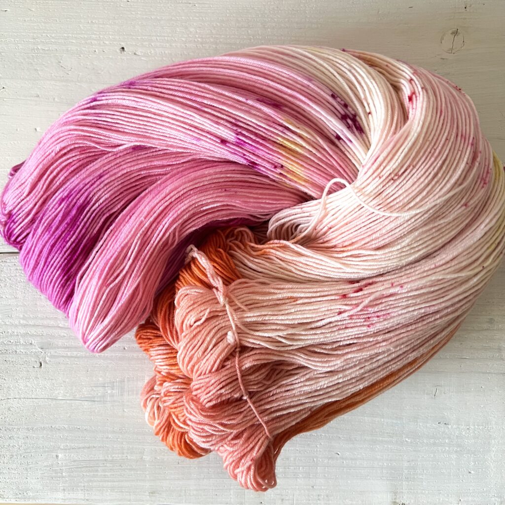 ピンクやオレンジグラデーションの手染め毛糸のカセをほどいた色の入り方
