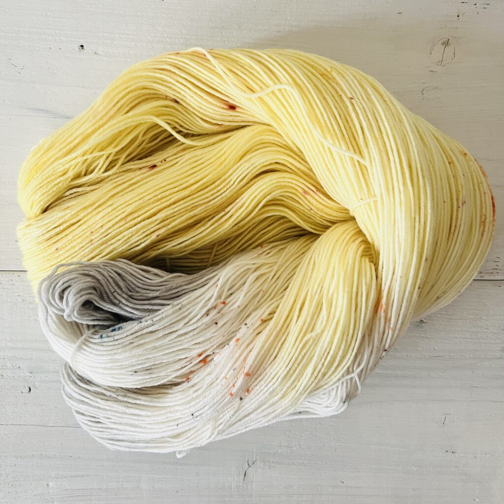 イエローや灰のグラデーションの手染め毛糸のカセをほどいた色の入り方