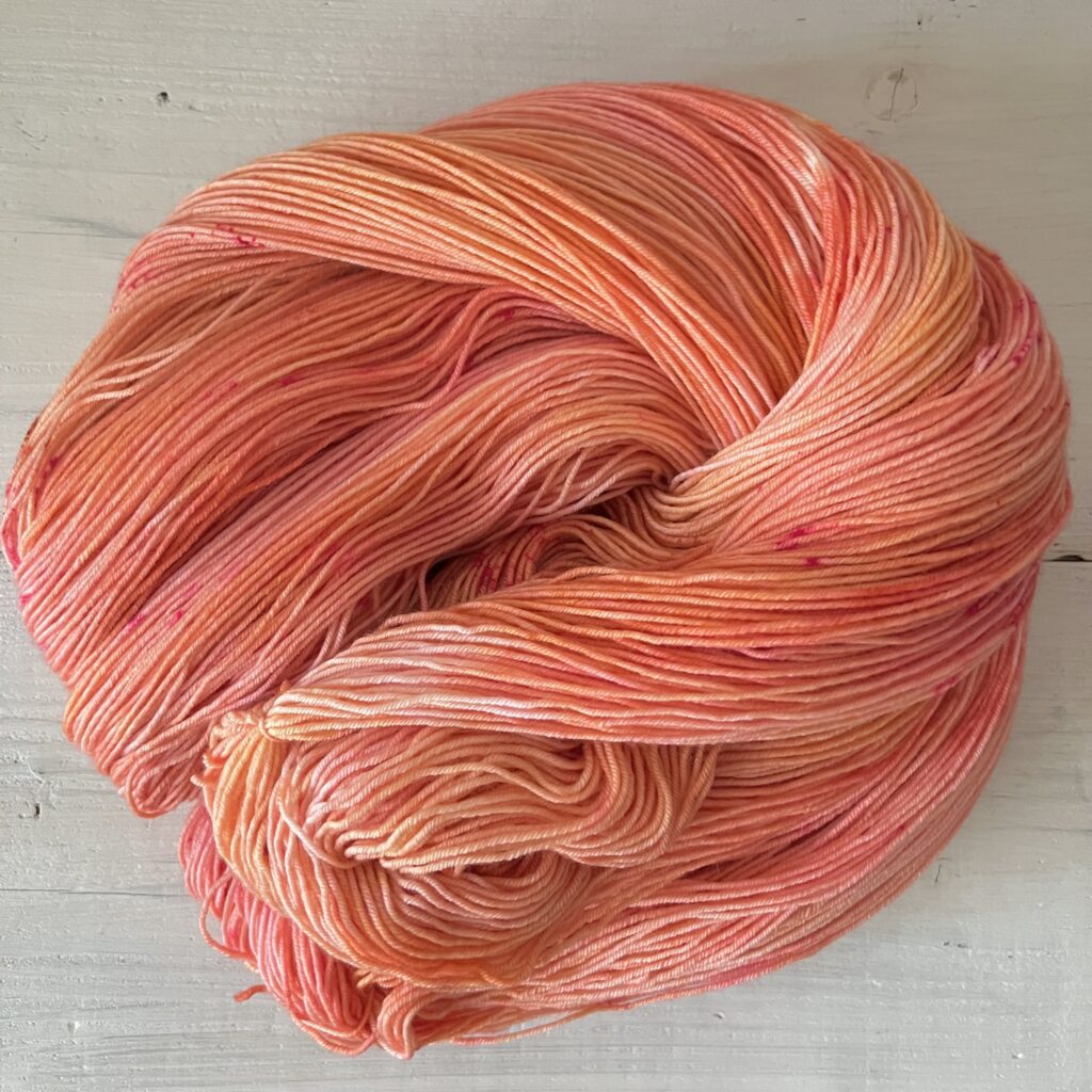 ピンクやオレンジグラデーションの手染め毛糸のカセをほどいた色の入り方
