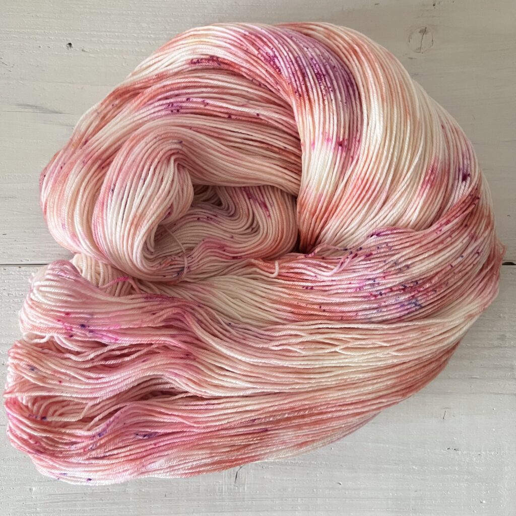 ピンクやオレンジグラデーションの手染め毛糸のカセをほどいた色の入り方