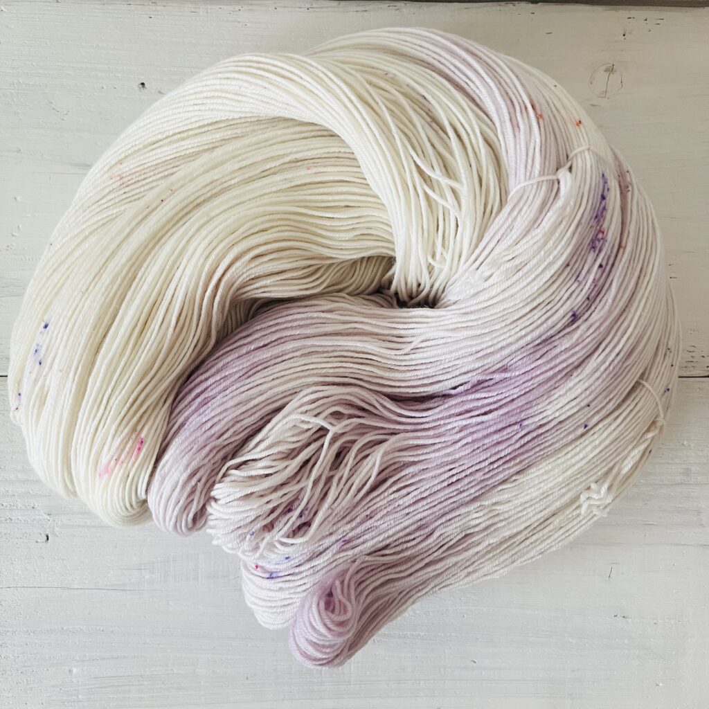 ラベンダーやアイボリーのグラデーションの手染め毛糸のカセをほどいた色の入り方