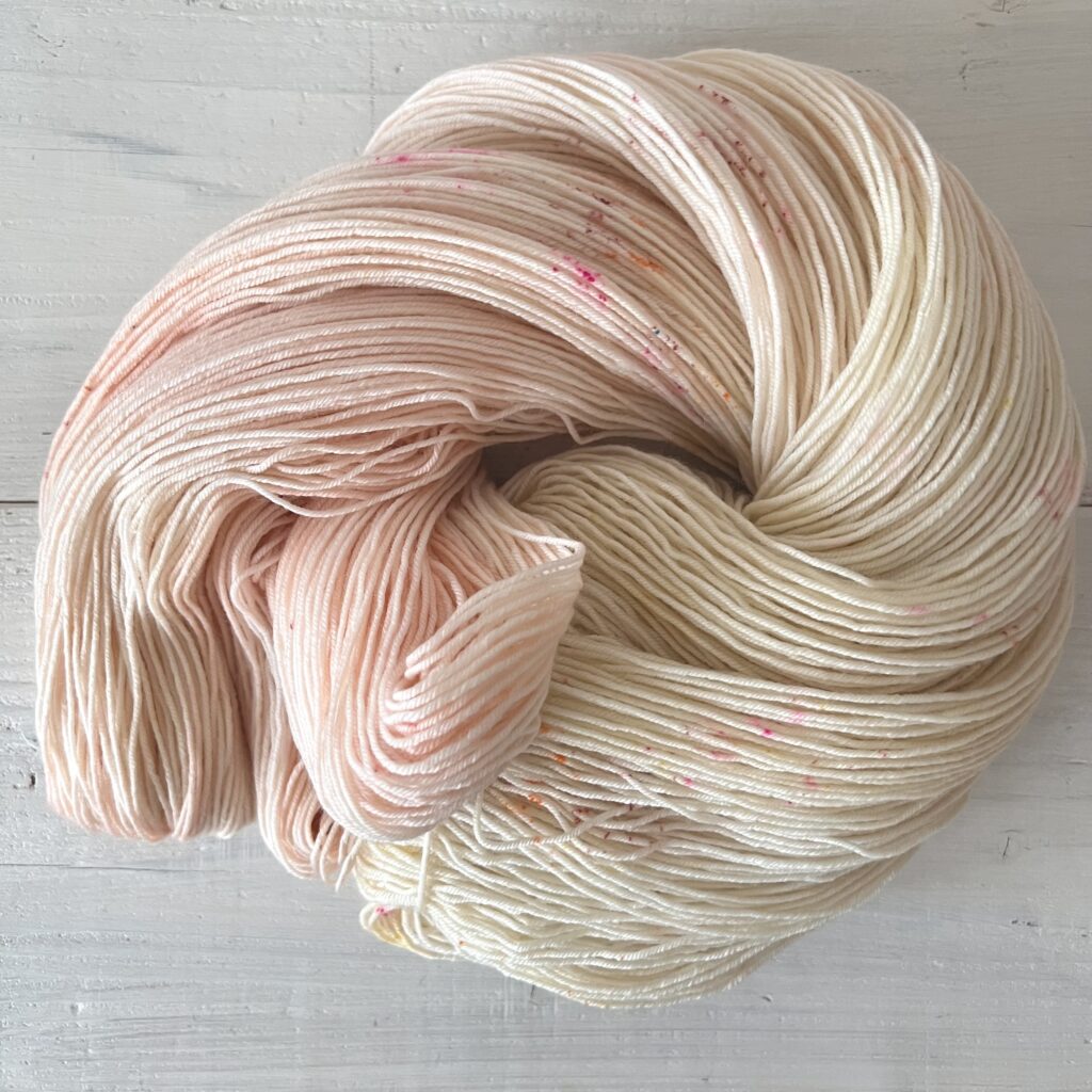 ピンクやイエローアイボリーグラデーションの手染め毛糸のカセをほどいた色の入り方